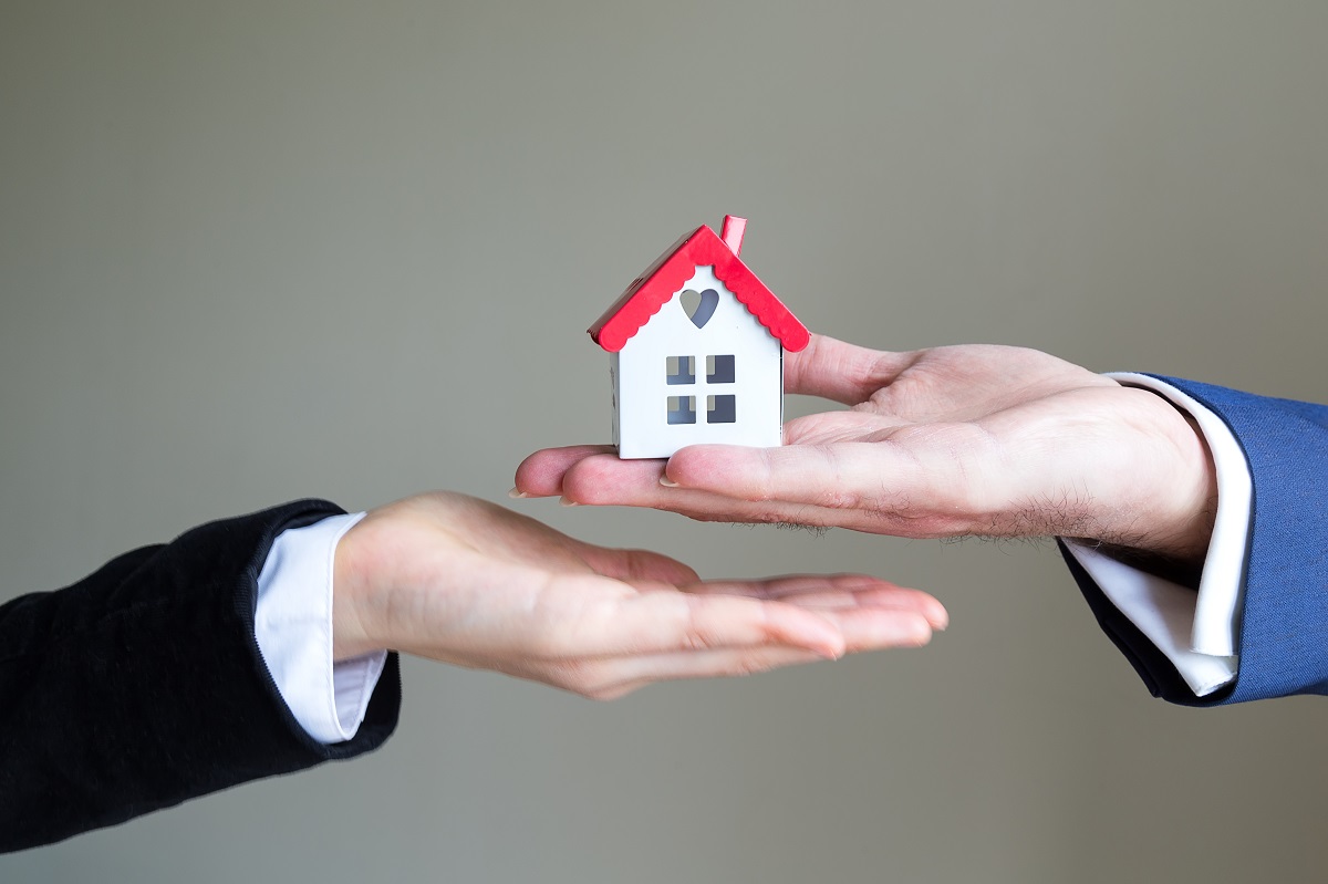 Person giving a toy house to another person