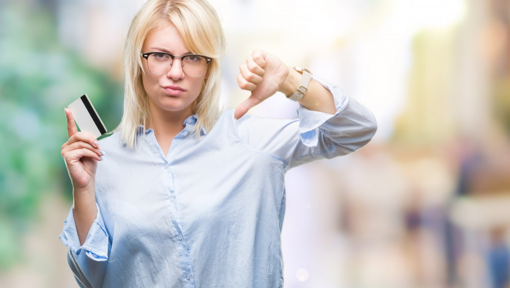 a woman with a credit card showing a thumbs down