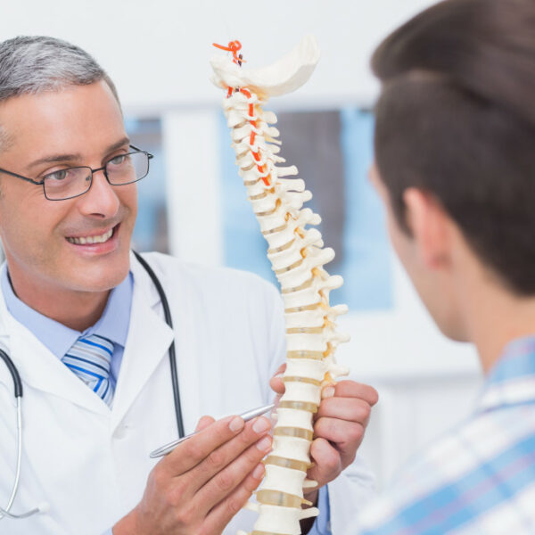 Doctor showing anatomical spine to his patient in medical office