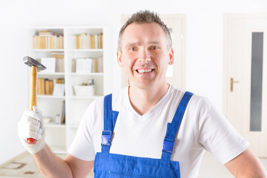 A old contractor happily showing his hammer standing in office 