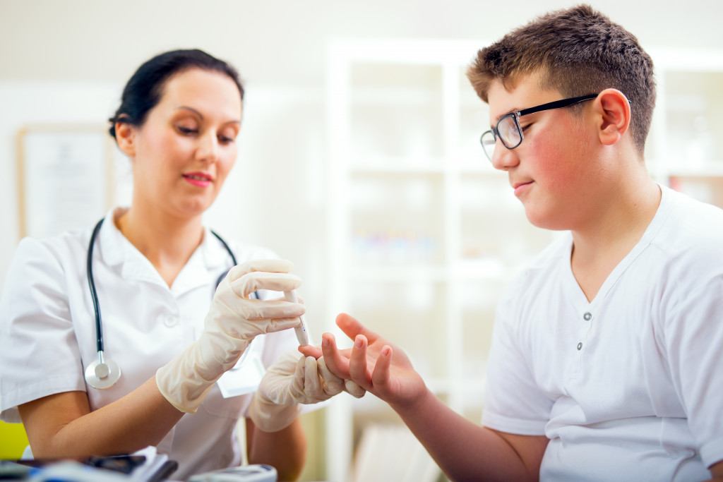 nurse measuring blood sugar of male patient in clinic or hospital