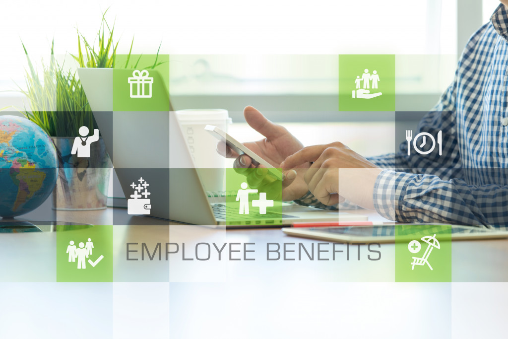 person using phone and laptop with employee benefits icons overlaid