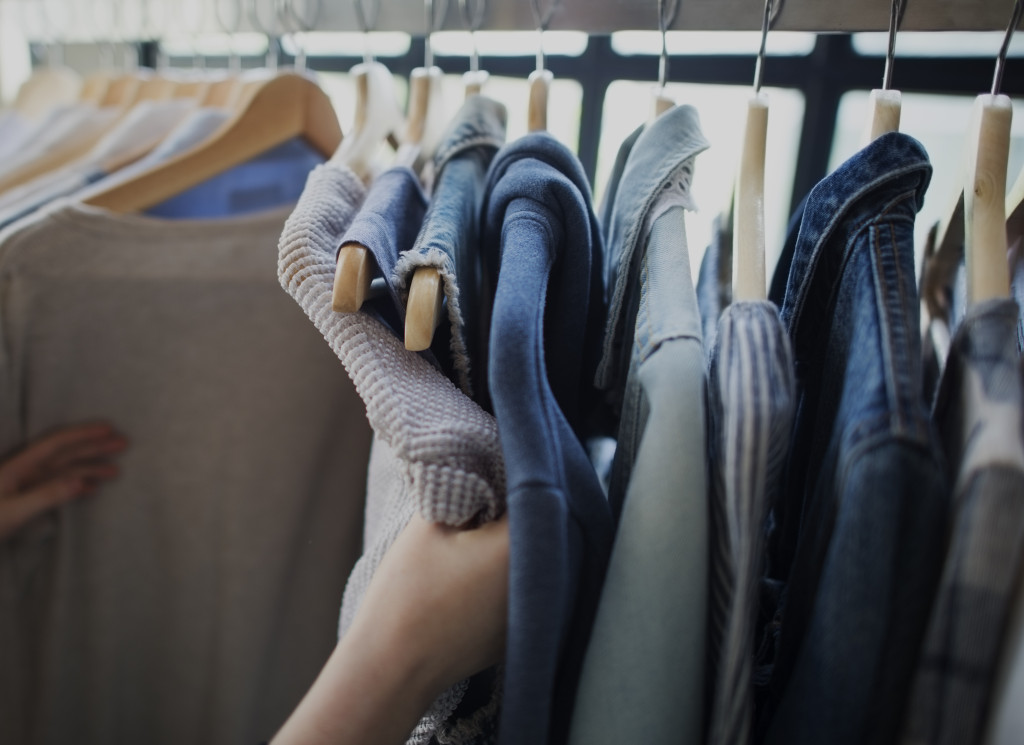 person rummaging through hangers of different wardrobe options