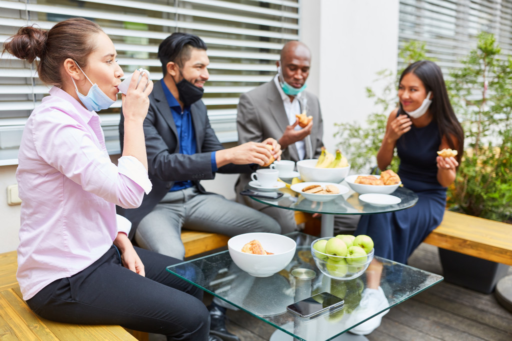 healthy employees eating outdoors with healthy food in table