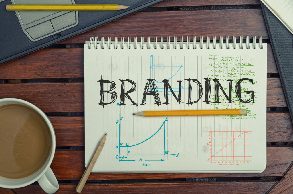 The word branding written on a notebook with pencils, coffee, and a laptop around it.