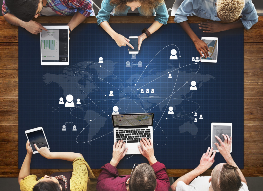 Business executives sitting at a conference table while holding mobile devices.