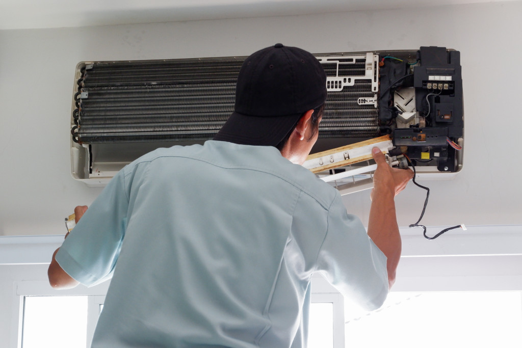 Technician fixing an air conditioning unit at an office.