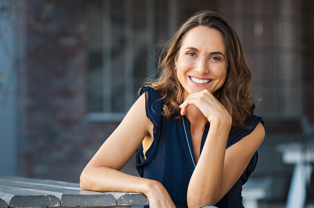 Mature woman smiling while sitting on a bench.