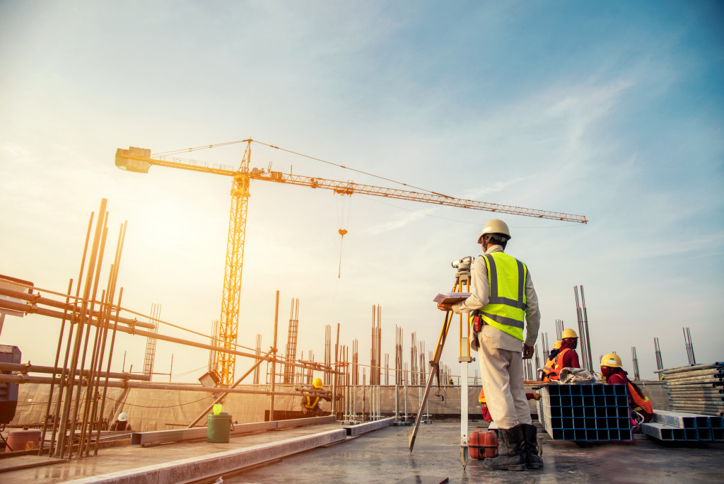 Construction surveyor checking figures with a tower crane in the background.