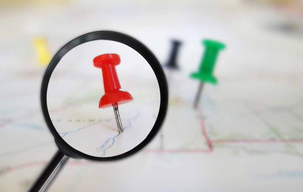 A red pin on a map under a magnifying glass