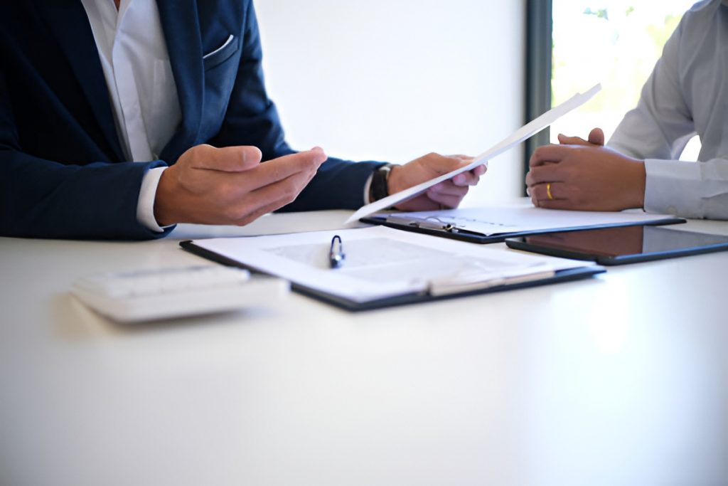 insurance agent in a suit handing a document to his client