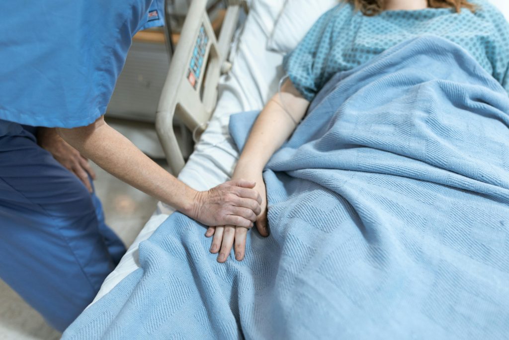 nurse holding a patient's hand lying on a hospital bed
